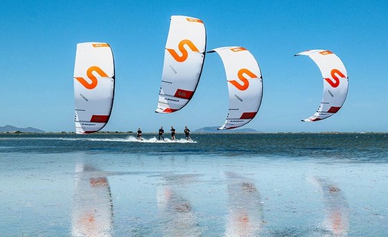 Four riders on freeride kites over flat, shallow water