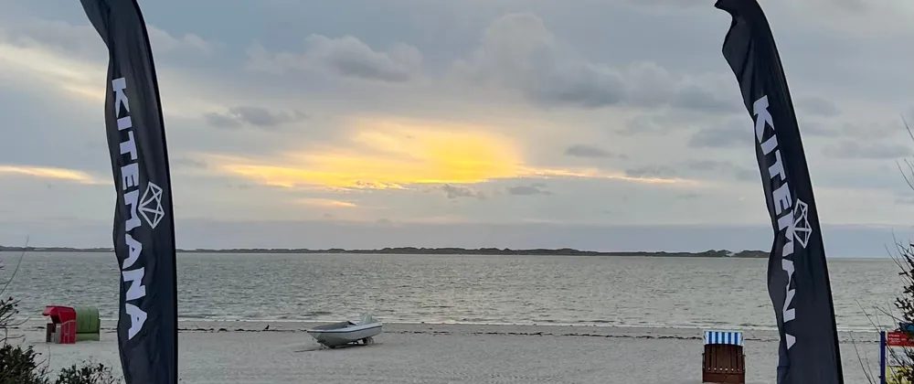 Boardwalk beach entry at Utersum between two Kitemana flags, with the information board on the right
