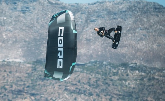A rider jumping with a Core kite in front of a rocky hillside