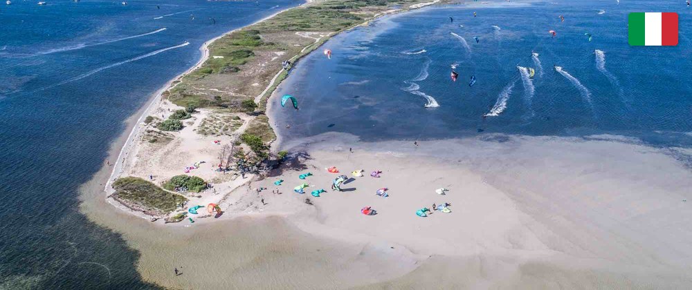 Aerial view of Punta Trettu: kites rigged on the sandbank and riders on the shallow lagoon