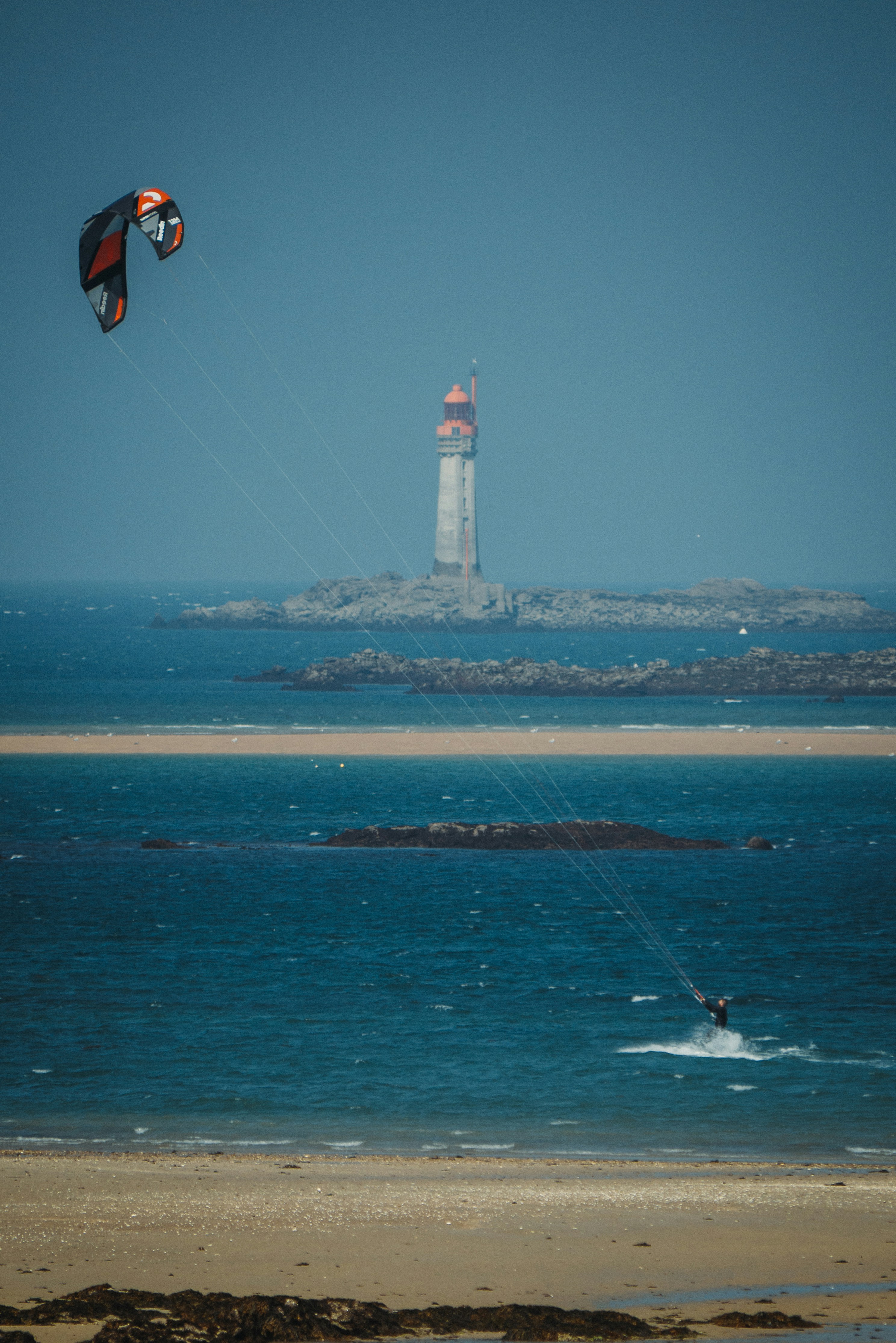 Kitesurf en Bretagne — rider devant un phare, vent de nord-ouest