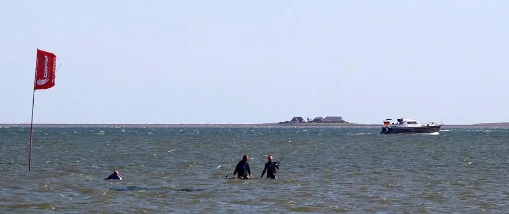 Kite lesson in standing-depth water at Wyk with an instructor and student next to a red flag