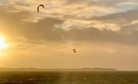 Kitesurfer jumping at sunset off Utersum with Amrum on the horizon