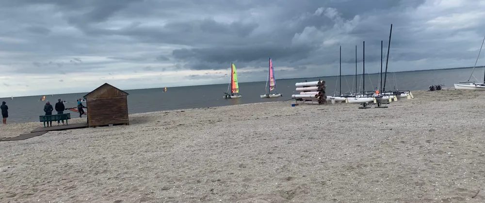 The beach in front of the Nieblum water sports school with catamarans and windsurfers on the water