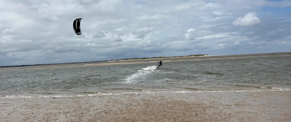 Kitesurfer riding the low-tide channel at Utersum next to a dry sand flat