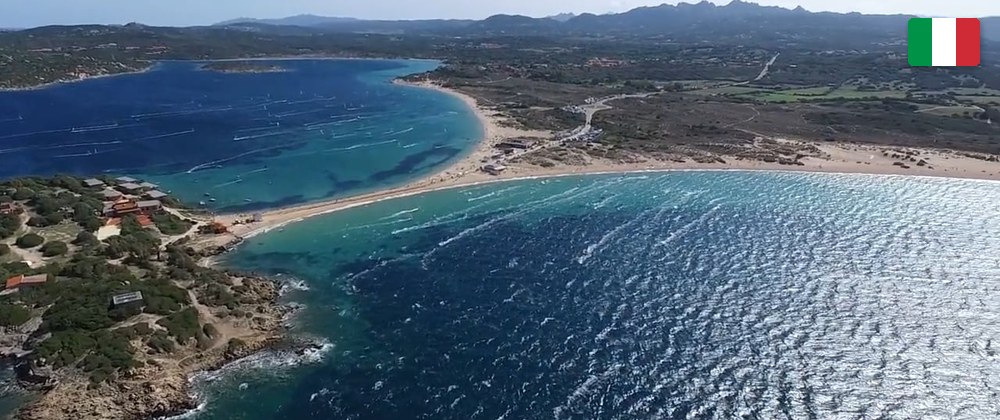 Aerial view of Porto Pollo: the two bays either side of the sandy causeway, with the mountains of Gallura behind